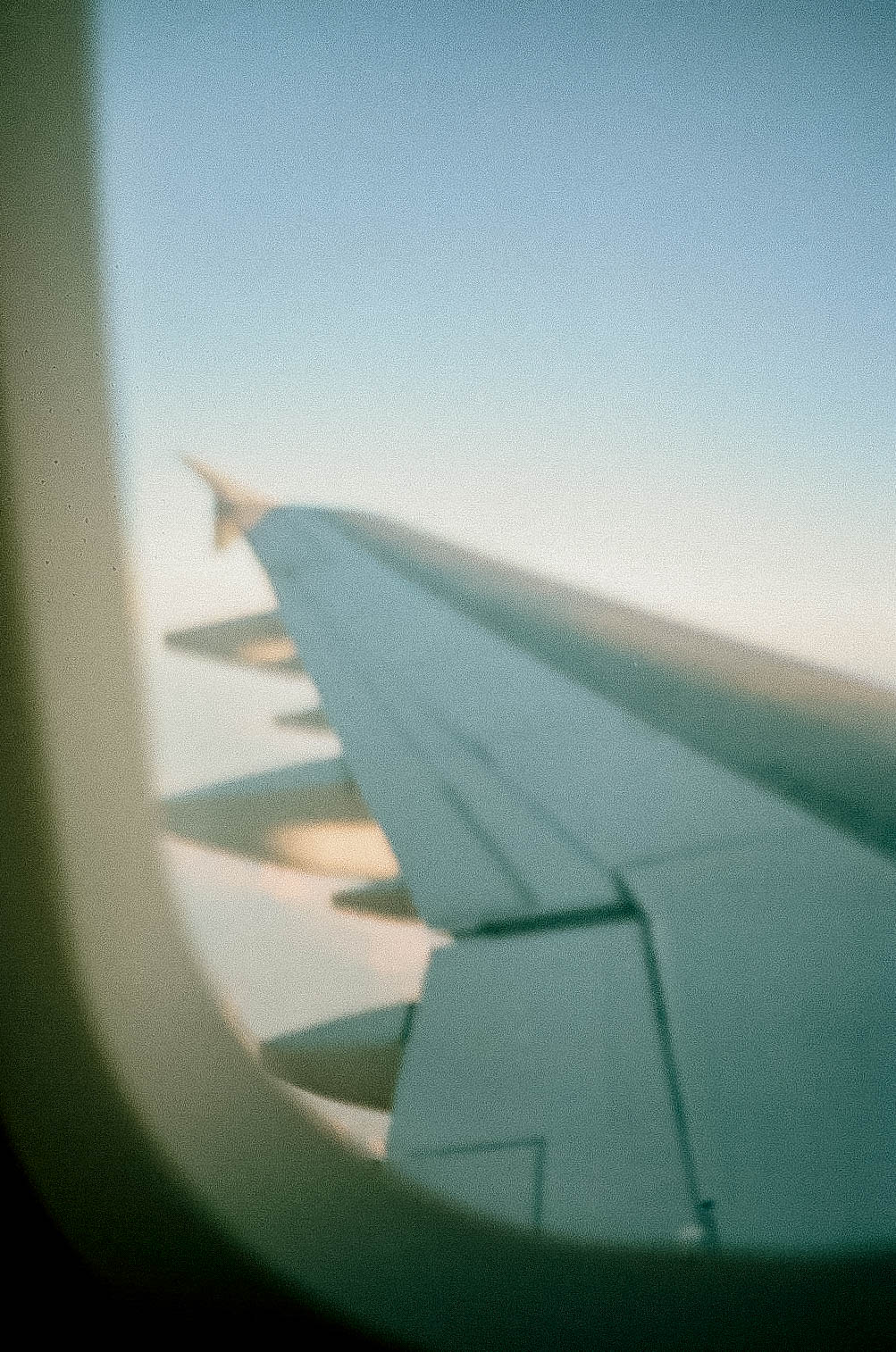 View from inside a plane looking out over a blue sky and the plane wing